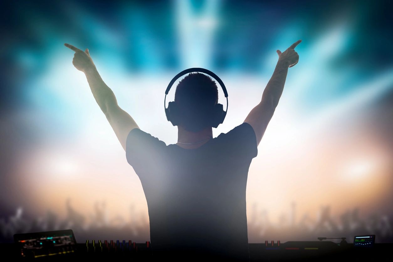 DJ silhouette with arms raised at concert